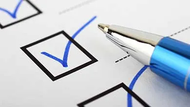 Close-up of a checklist with blue checkmarks and a blue pen.